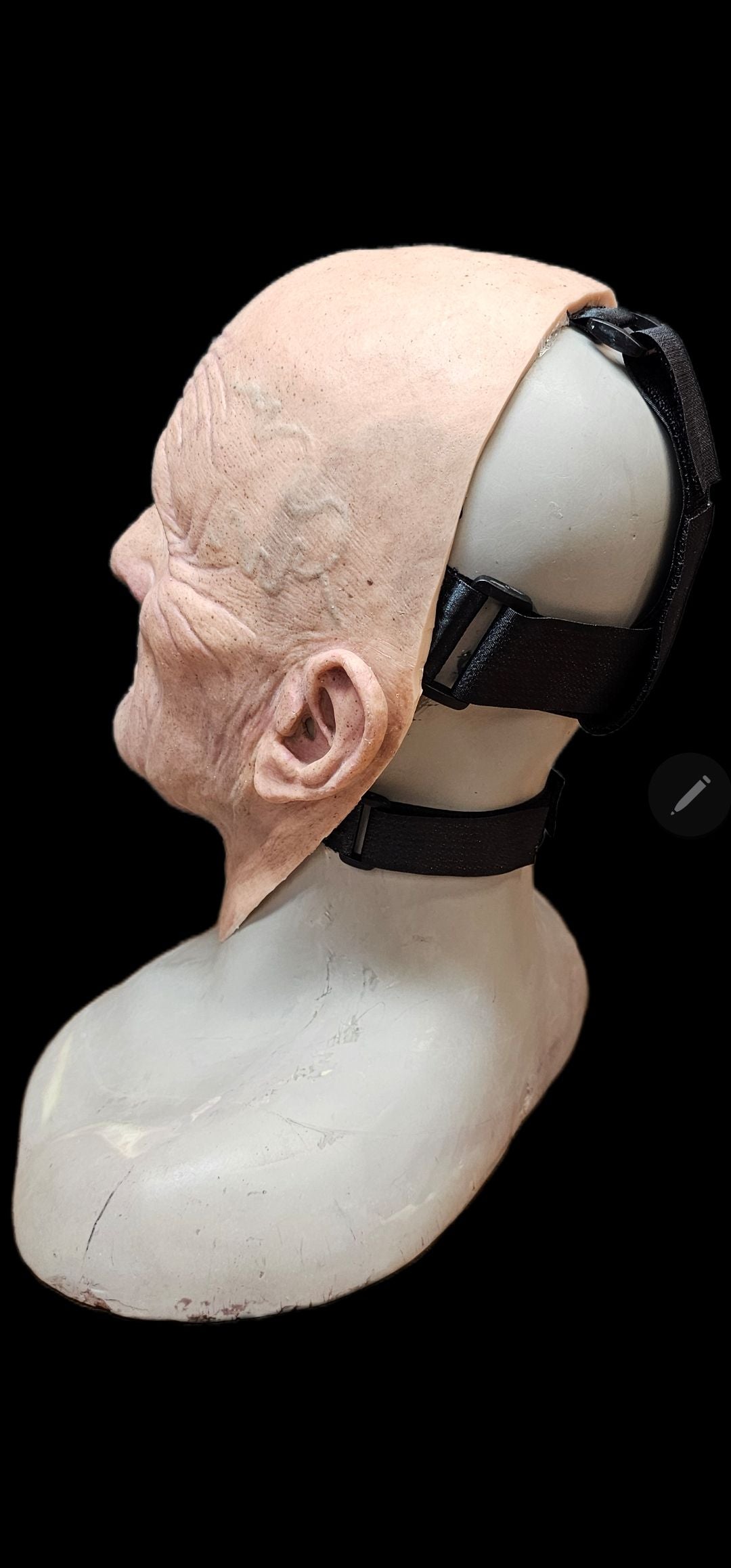 Mannequin head with a prosthetic scalp and black bandage on a black background